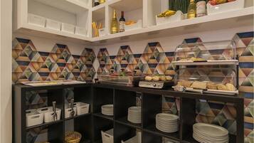 A modern kitchen with white shelves, a tiled backsplash, and a buffet counter with food items.