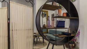 A living room with a round shelving unit, a blue sofa, and a dining area with a table and chairs. - Hotel Ciudad del Mar (Las Palmas de Gran Canaria)