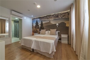 A double bed with a beige bedspread, a nightstand, a wall-mounted lamp, and a shower with a patterned door. - Hotel Ciudad del Mar (Las Palmas de Gran Canaria)