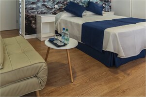 A hotel room with a bed, a small table with a glass, and a chair.