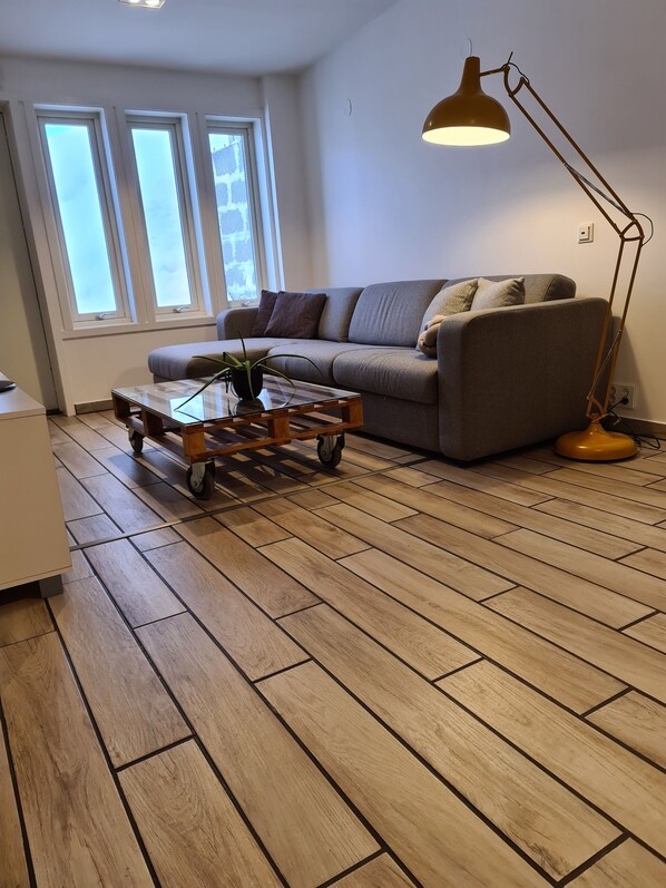 Sala de estar com sofá, mesa de centro com planta e luminária de chão.
