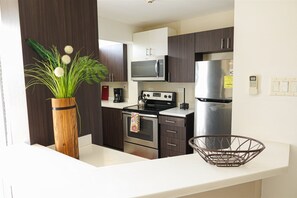 Enjoy cooking in this kitchen with dark cabinets, stainless steel appliances, and a white countertop.