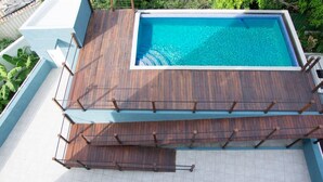 Une piscine rectangulaire entourée d’une terrasse en bois.