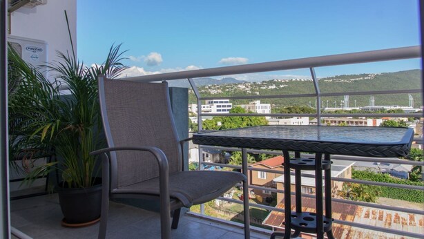 Un balcon avec une chaise, une petite table et un pot de fleurs.