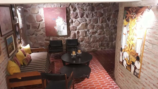 Une pièce chaleureuse avec un mur en pierre, une table ronde décorée de bougies, un canapé agrémenté de coussins à rayures et un tableau.
