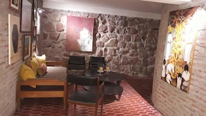 Une pièce chaleureuse avec un mur en pierre, un lit avec des oreillers, une table avec des chaises et un tableau accroché au mur.