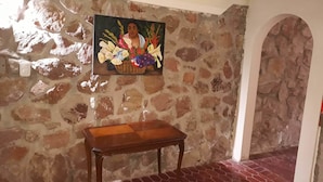 Une pièce avec un mur en pierre, un banc en bois et un tableau représentant des fleurs.