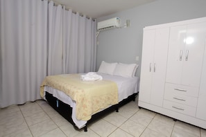 Un dormitorio con cama, armario y aire acondicionado.