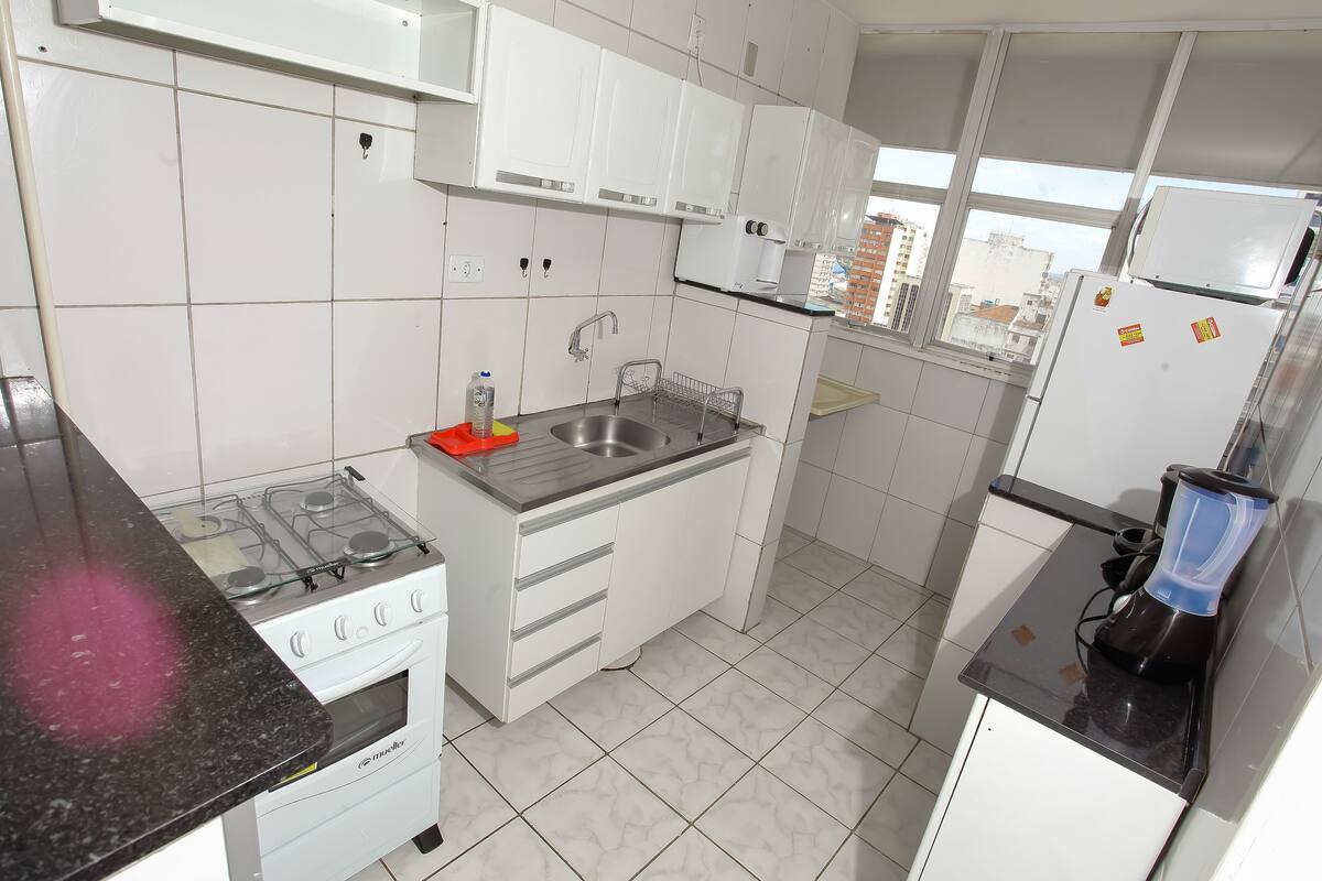 A modern kitchen with white cabinets, a gas stove, a sink, and a coffee maker.