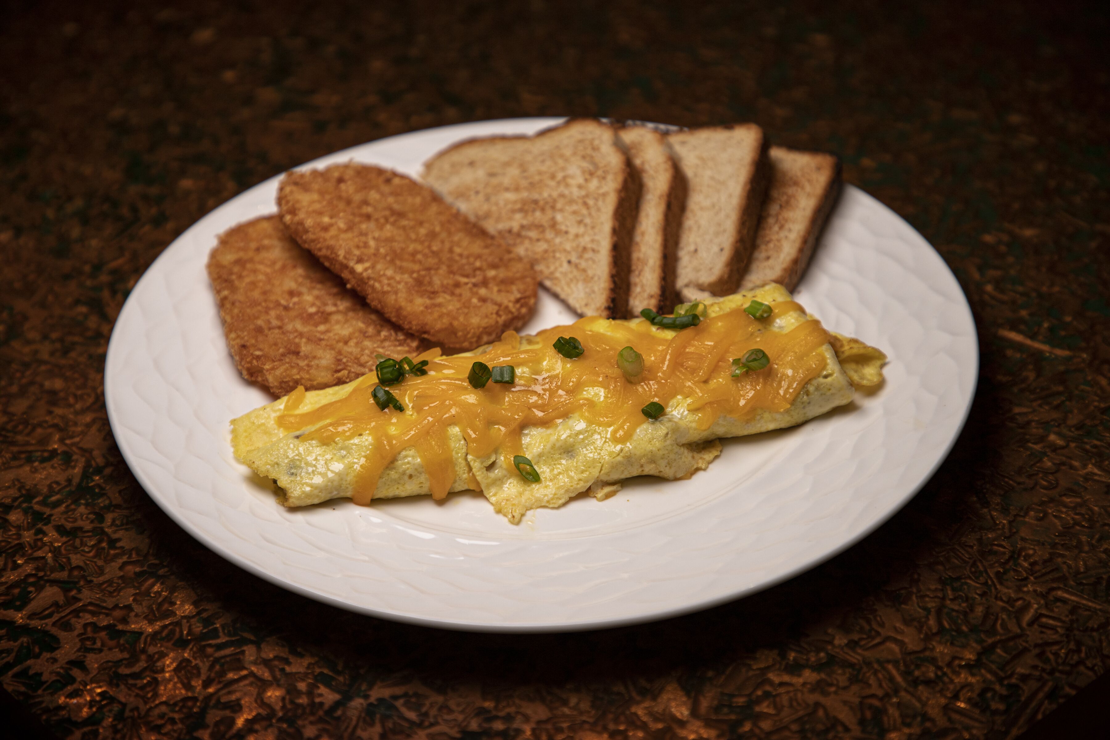 A plate with an omelet, toast, and a side dish.