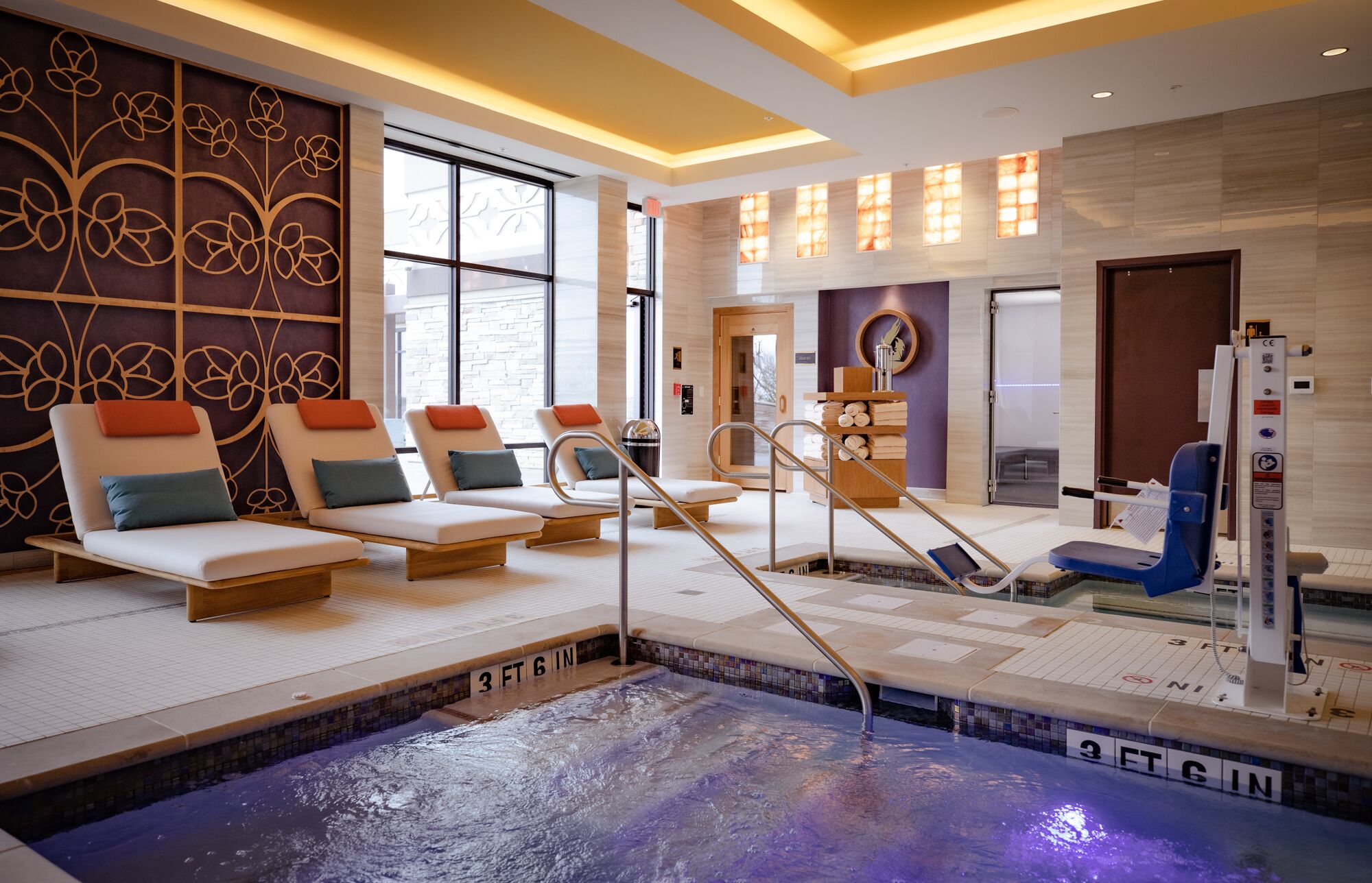 Een moderne spa met een bubbelbad, lounge stoelen en een stoomruimte.