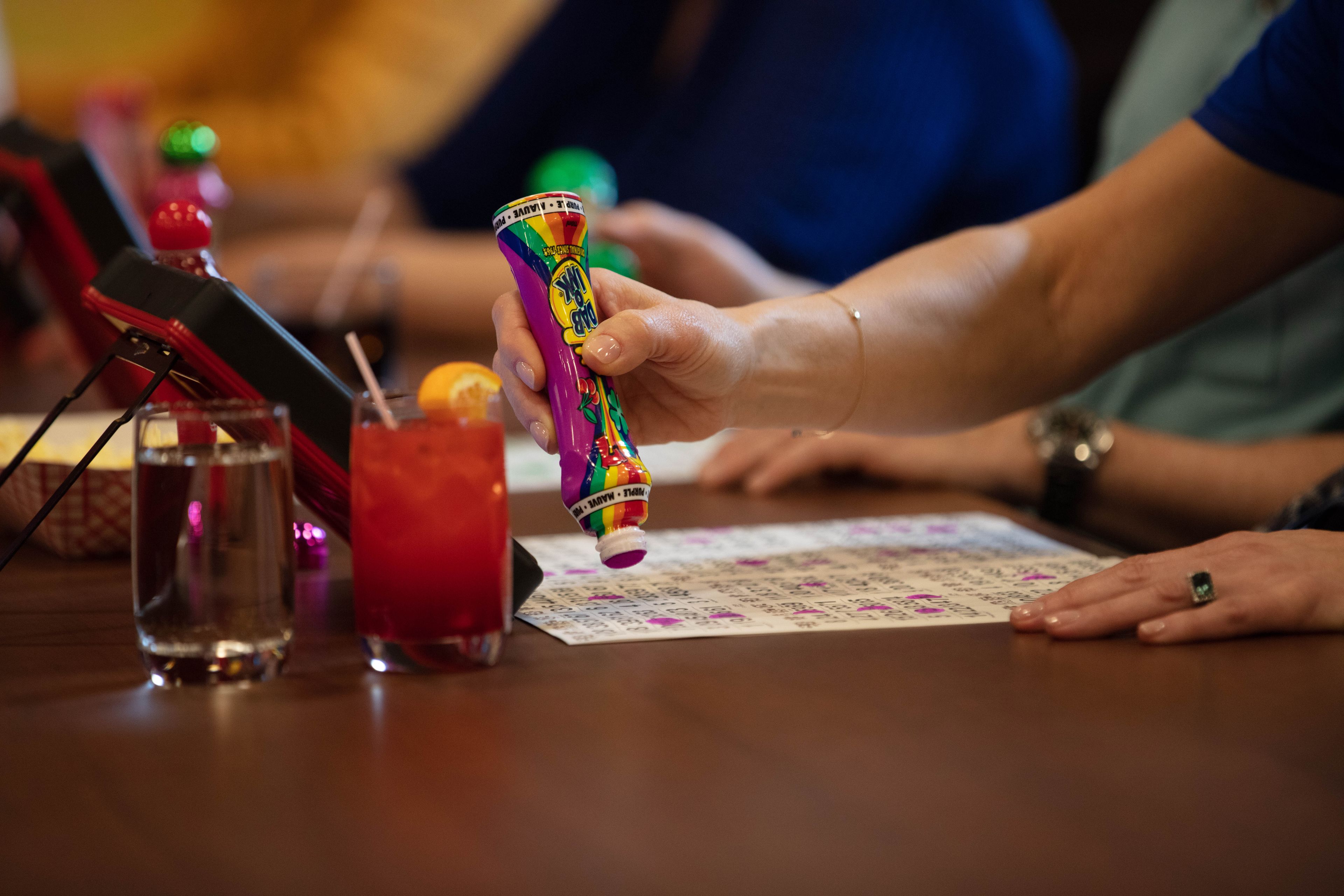 A person pouring a colorful drink from a bottle into a glass.