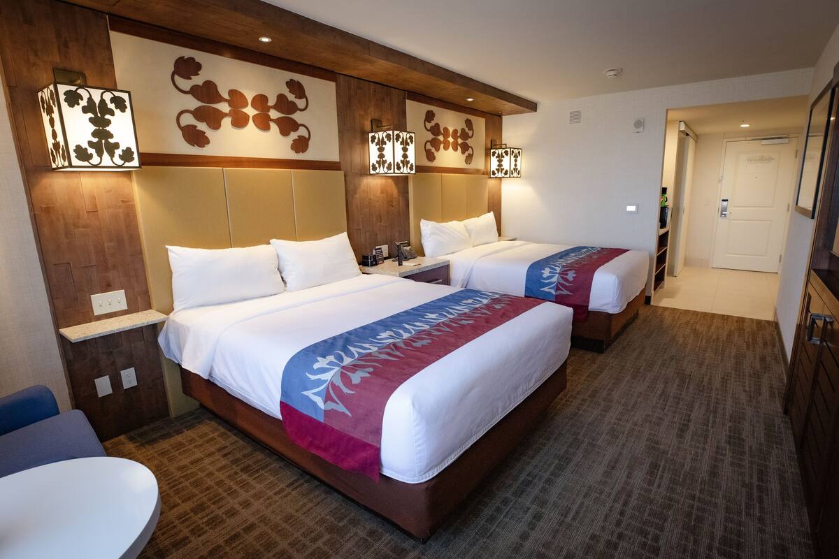 Ein Hotelzimmer mit zwei Betten, einem kleinen Tisch und einer Tür.