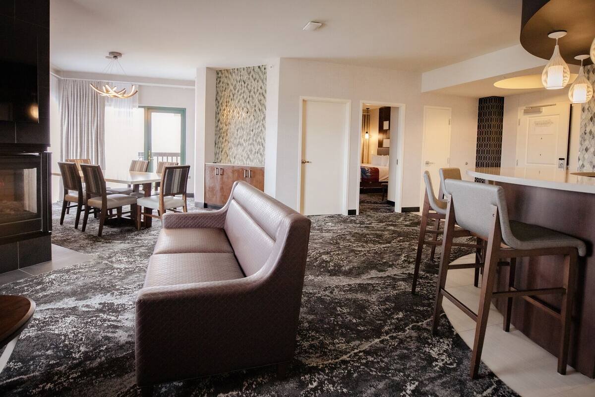 Ein modernes Hotelzimmer mit Kamin, einer Couch, einem Essbereich und einer Küchenbar.