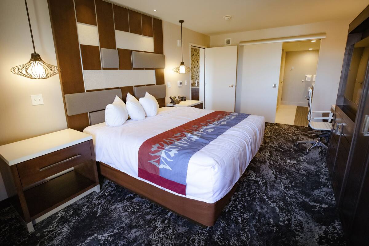Ein Hotelzimmer mit einem großen Bett, einem Nachttisch, einem Kleiderschrank und einem Badezimmer mit Dusche und Waschbecken.