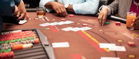 A casino table with playing cards, chips, and a drink.