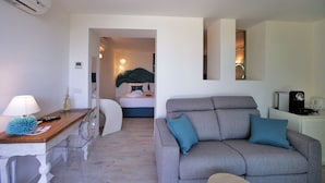 Un soggiorno moderno con un divano grigio, un tavolino con una lampada e un letto sullo sfondo.