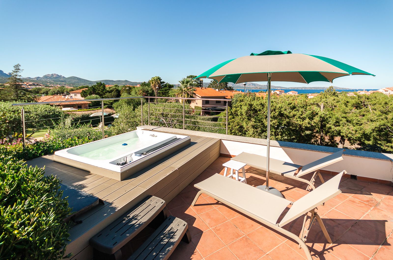 Una terraza en la azotea con un jacuzzi, mobiliario exterior y vistas del paisaje circundante.