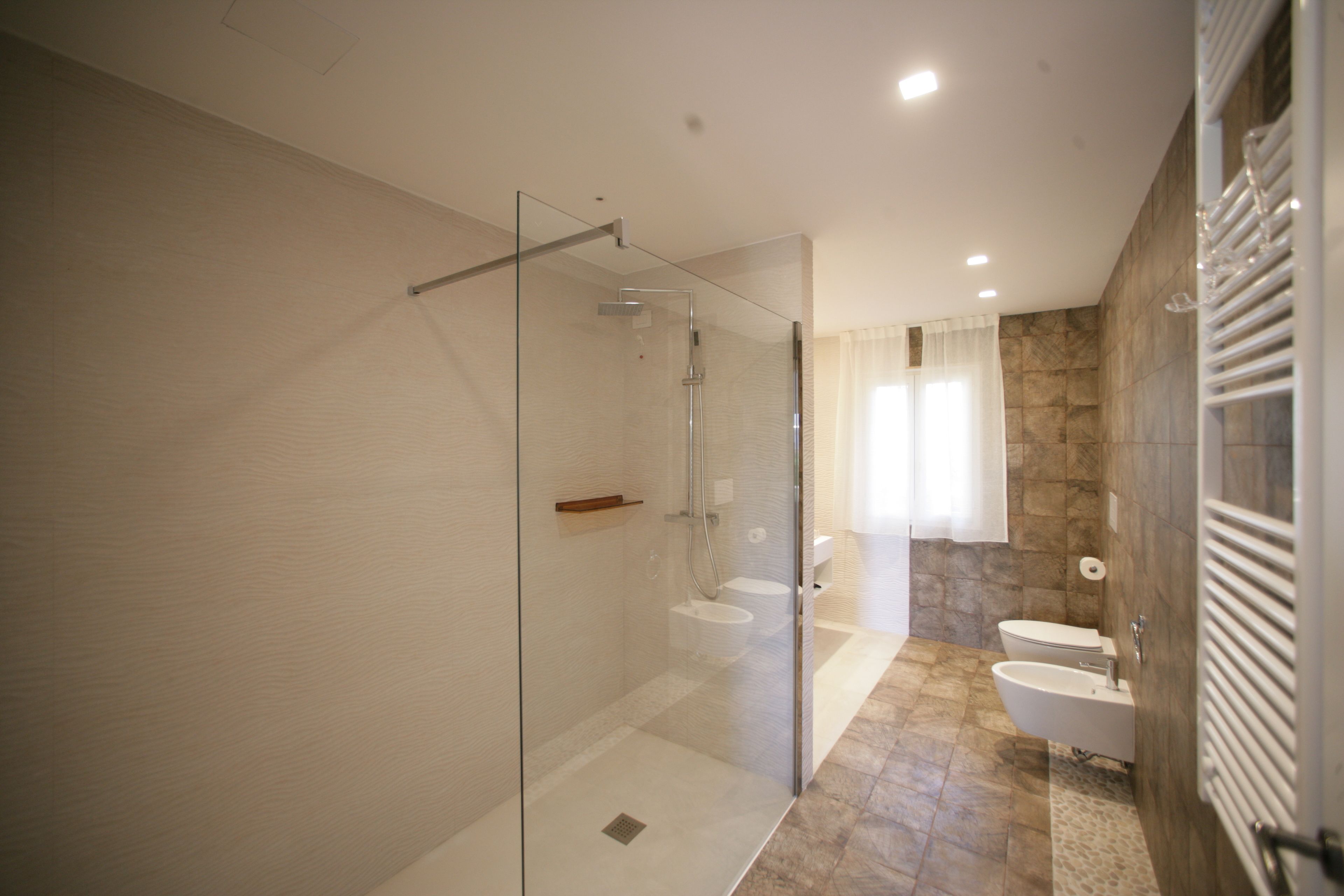 A modern bathroom with a glass-enclosed shower, a freestanding bathtub, and a toilet.
