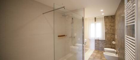 A modern bathroom with a glass-enclosed shower, a freestanding bathtub, and a toilet.