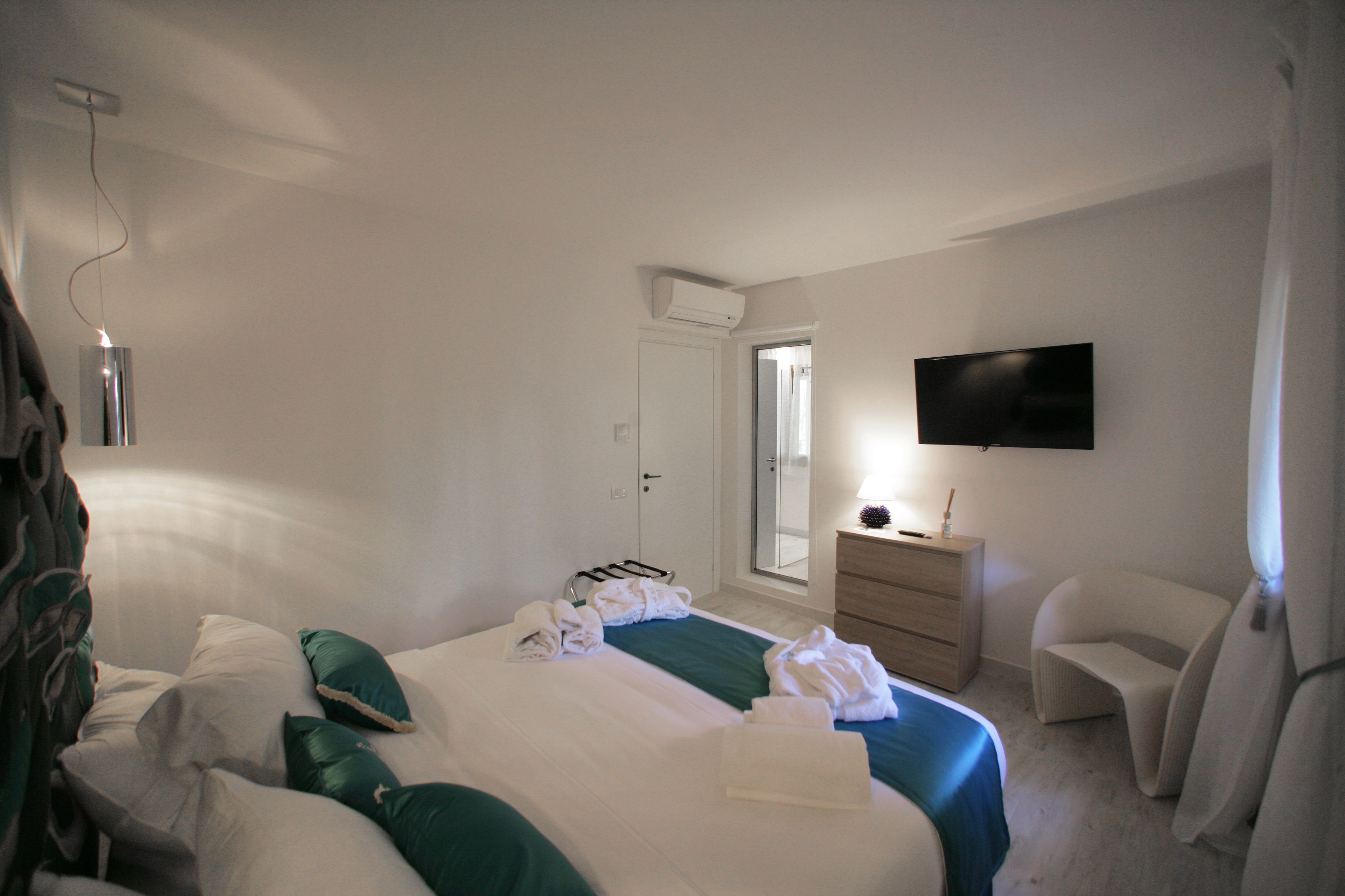 Una habitación de hotel con cama, cómoda, televisor y una silla.