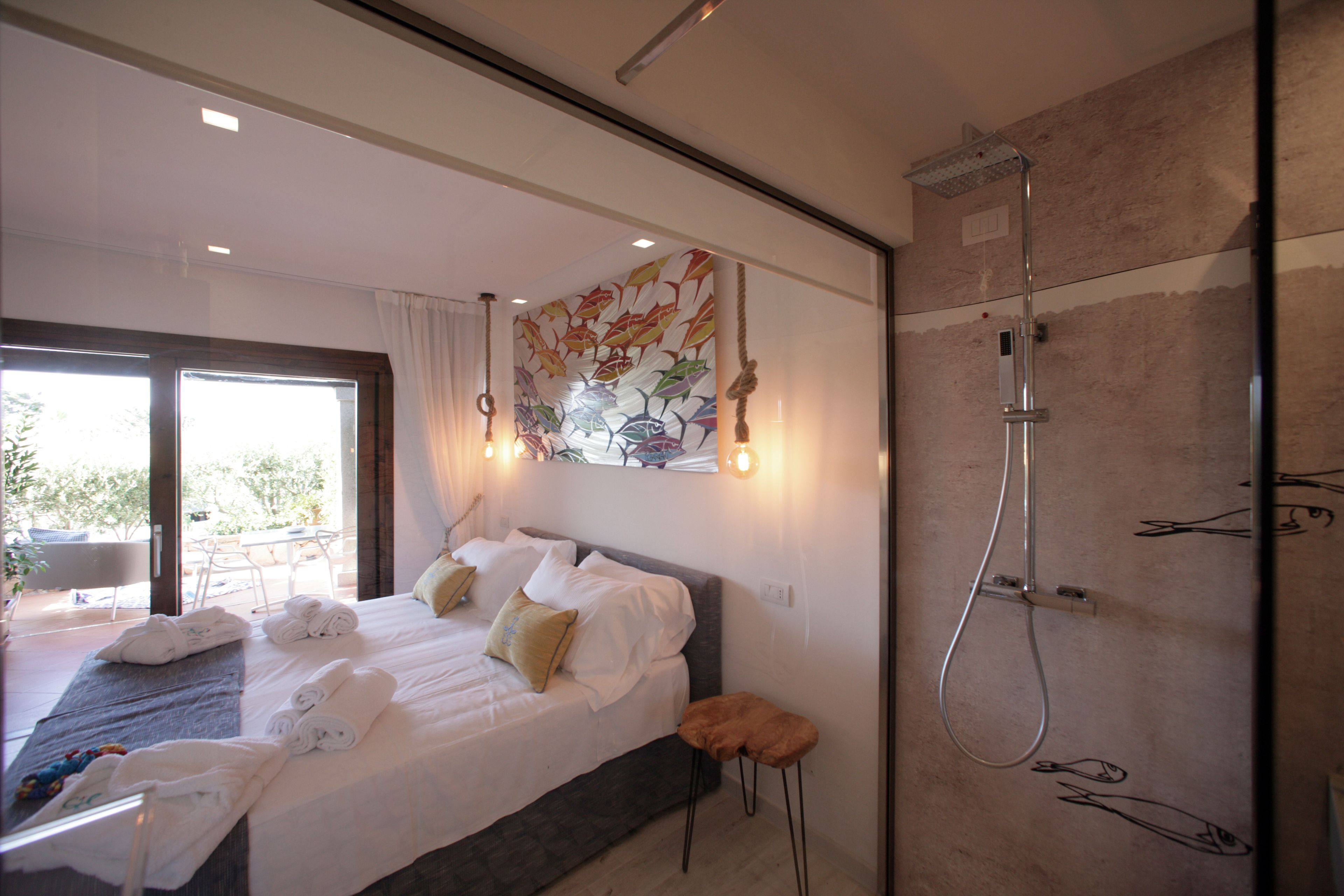Quarto de hotel moderno com uma cama grande, chuveiro e uma varanda com área de estar ao ar livre.