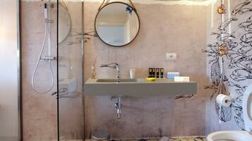 Een moderne badkamer met een vloer met een geometrisch patroon, een glazen douchecabine, een wastafel met spiegel erboven en een toilet met een decoratieve douchegordijn.