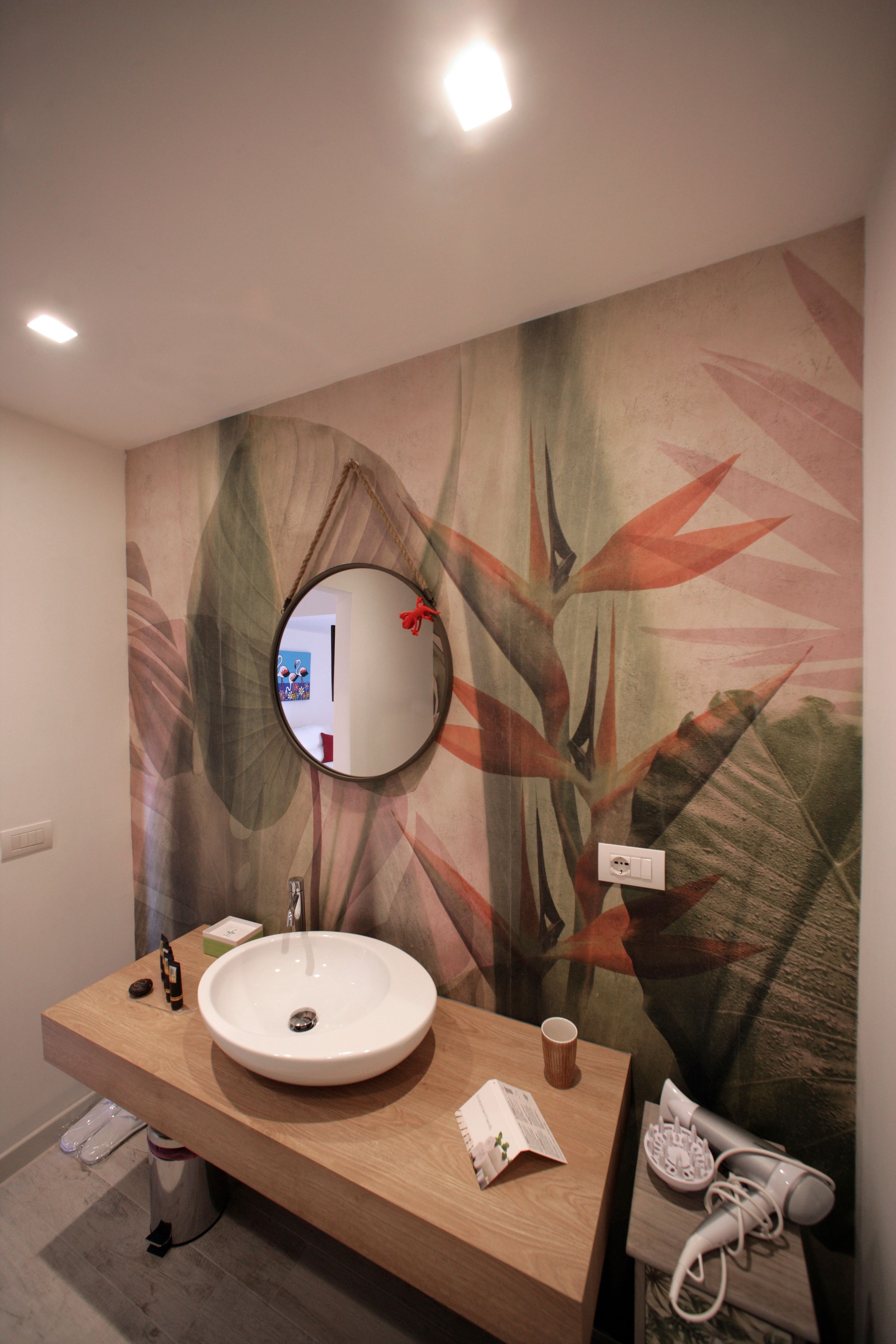 Une salle de bain avec un meuble-lavabo en bois, un lavabo blanc, un miroir rond et un porte-serviettes.