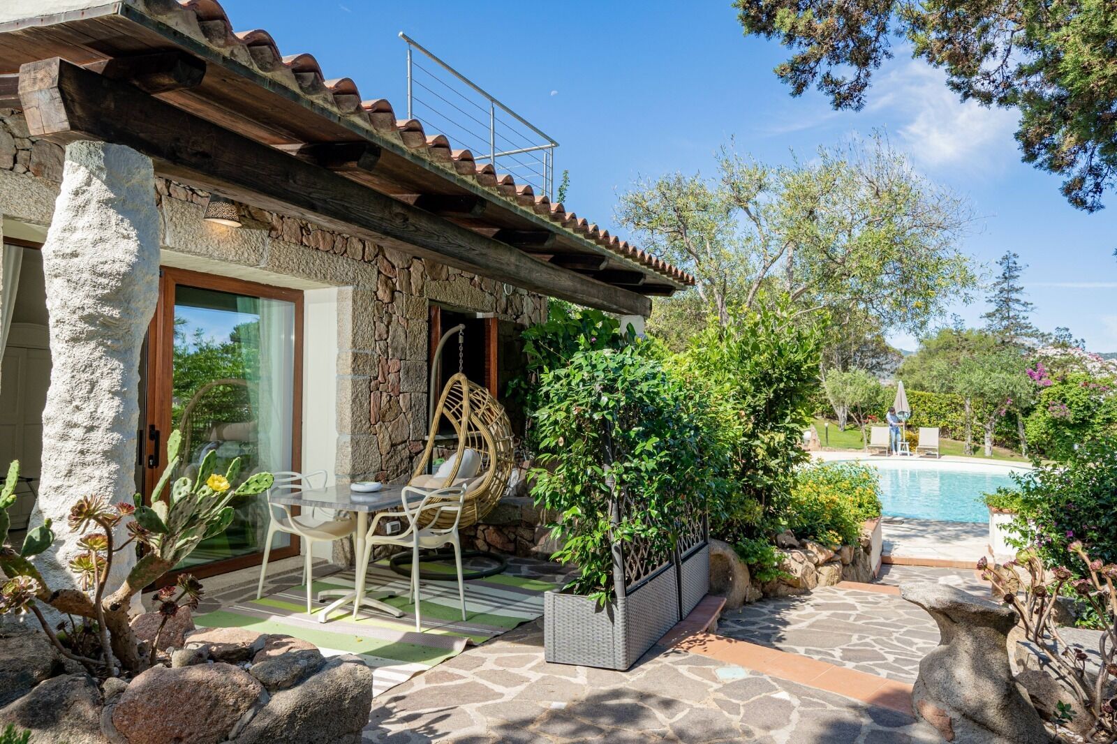 Ein Steinhaus mit Terrasse, einer Hängematte und einem Schwimmbecken.
