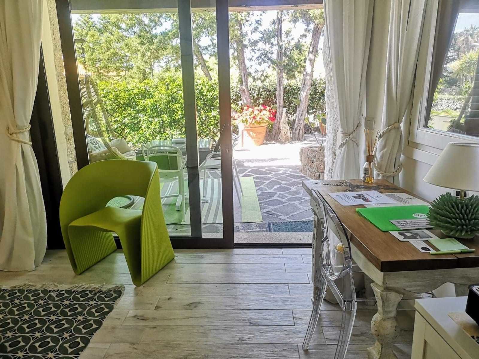 Habitación con puerta de vidrio corredera que da a un espacio exterior con sillas y plantas en macetas.
