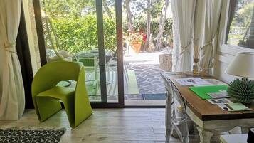 Habitación con puerta de vidrio corredera que da a un espacio exterior con sillas y plantas en macetas.