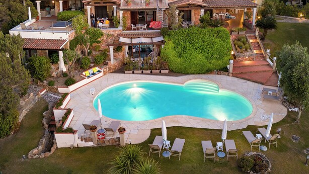 Un'ampia casa con piscina, diversi balconi e un giardino.