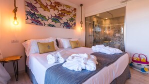 Una camera d'albergo con un letto, asciugamani, un quadro e una zona doccia.