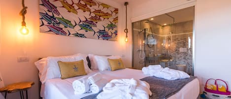 A hotel room with a bed, towels, a painting, and a shower area.