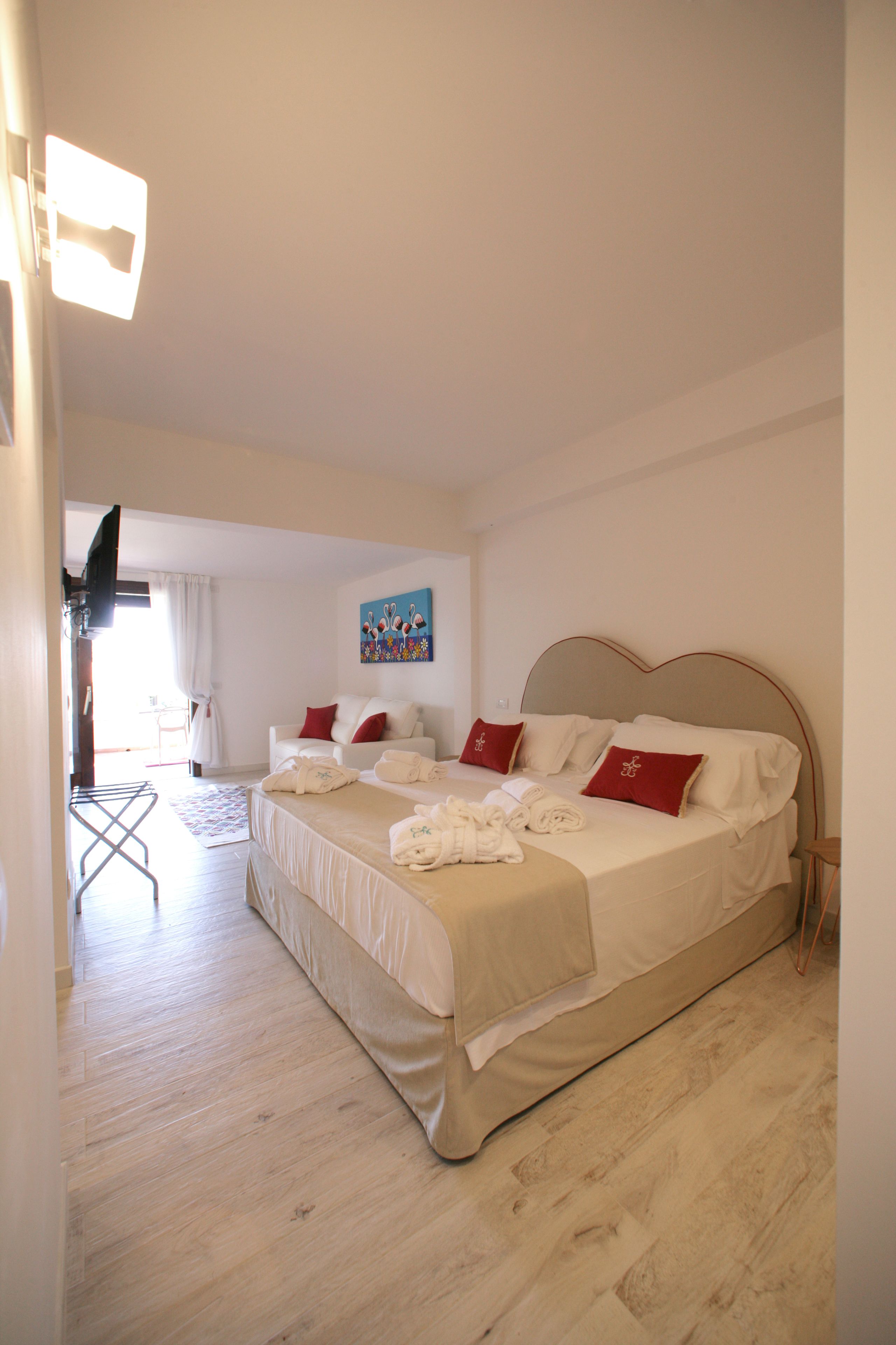 A hotel room with a large bed, a flat-screen TV, and a painting on the wall.