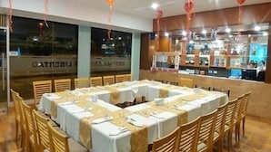 Un restaurante con varias mesas preparadas para comer, sillas de madera y adornos rojos colgantes.