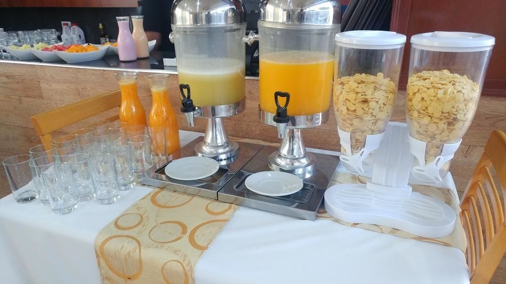 A breakfast buffet setup with juice dispensers and cereal containers.