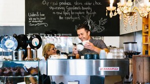 A coffee shop interior with a chalkboard displaying a message about a new produce store opening. - Kilcunda Ocean View Motel (Kilcunda)