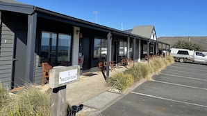 A modern building with a reception area marked by a sign, outdoor seating, and a parking lot. - Kilcunda Ocean View Motel (Kilcunda)