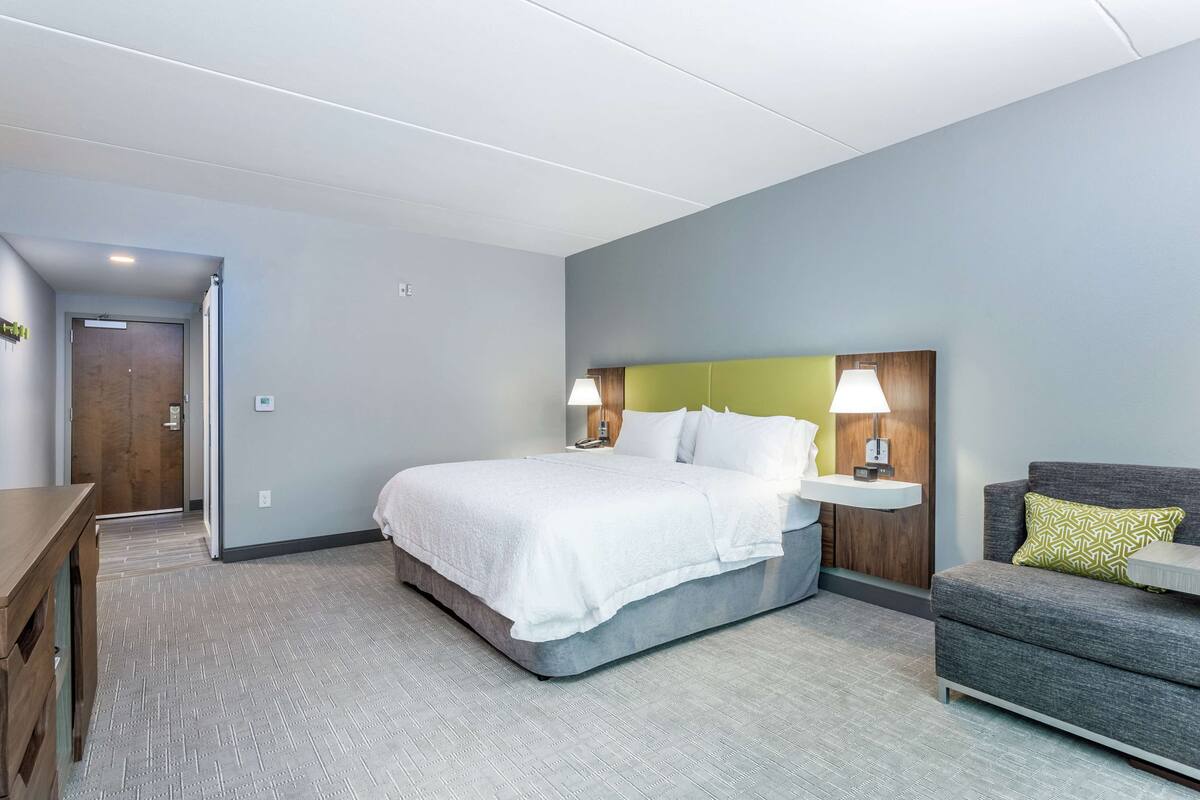 A hotel room with a bed, bedside tables, a sofa, and a wooden door.
