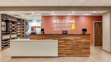 Un mostrador de recepción con un letrero que dice "Welcome to the Honey Bee State", el logotipo de Hilton y un área de recepción con un mostrador y estanterías de madera.
