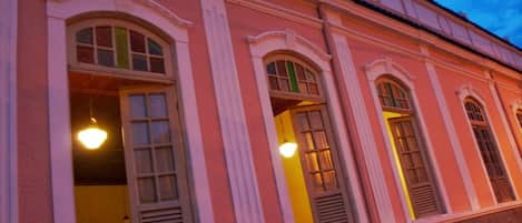 Fachada de edificio con ventanas arqueadas y lámparas colgantes.