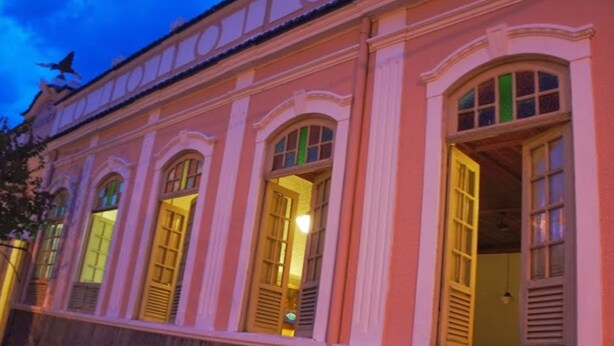 Un edificio rosa con ventanas y puertas arqueadas, algunas de las cuales están abiertas.