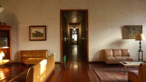 Un salón con piso de madera, dos sofás de cuero, una mesa de centro, una lámpara y un cuadro enmarcado en la pared.