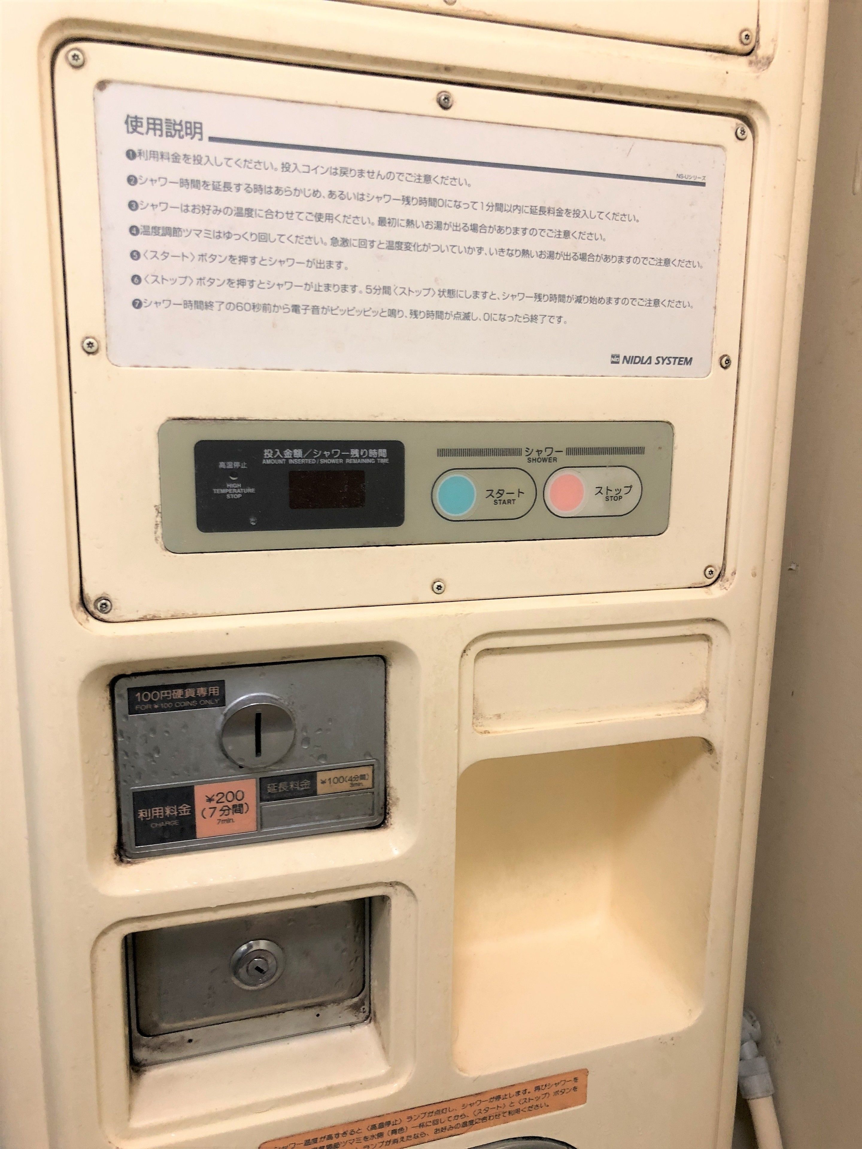 A public restroom with a sign providing usage instructions, a temperature sensor, a coin-operated button, and a timer display.