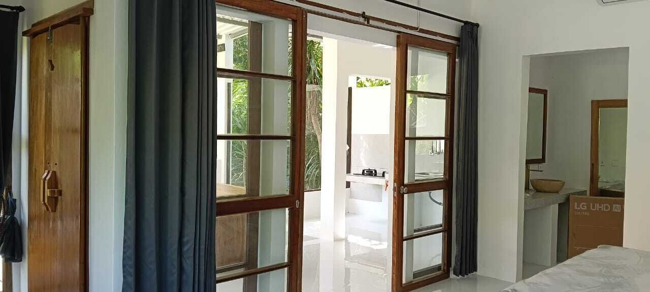 Quarto com uma grande porta de vidro deslizante que dá para uma varanda, guarda-roupa de madeira e banheiro com espelho e pia.