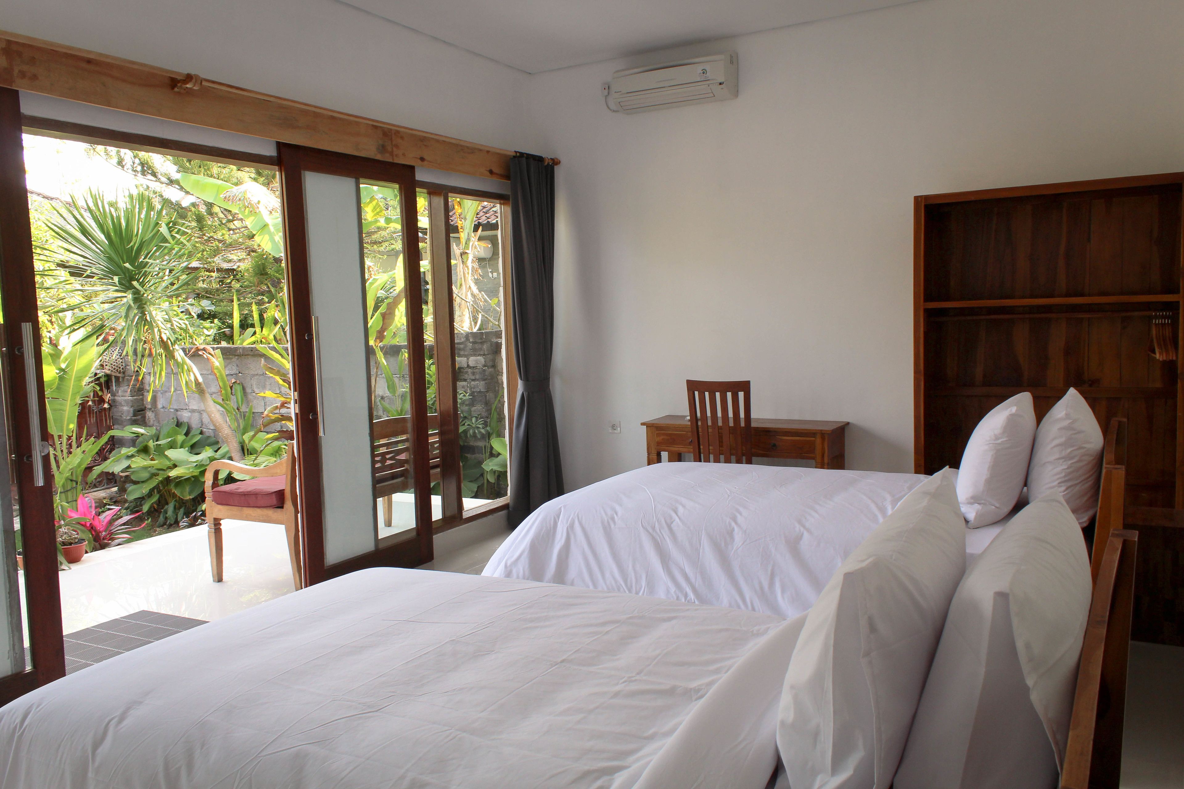 A bedroom with two beds, a wooden chair, and a small table.