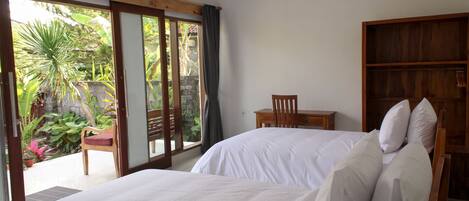 A bedroom with two beds, a wooden chair, and a small table.
