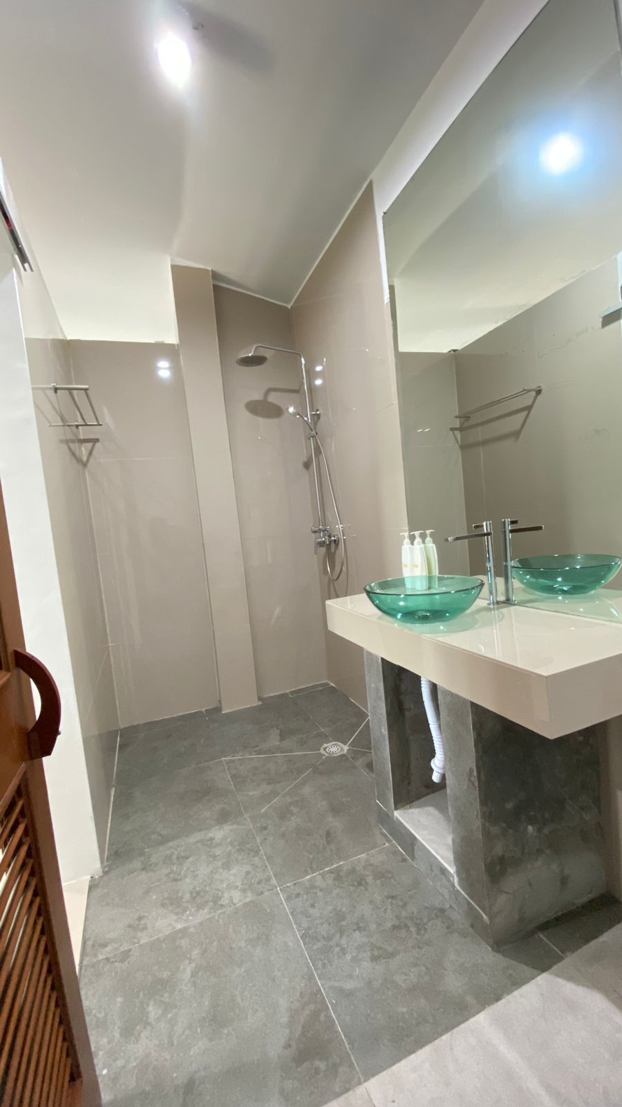 A modern bathroom with a glass bowl sink, a shower, and a walk-in shower.
