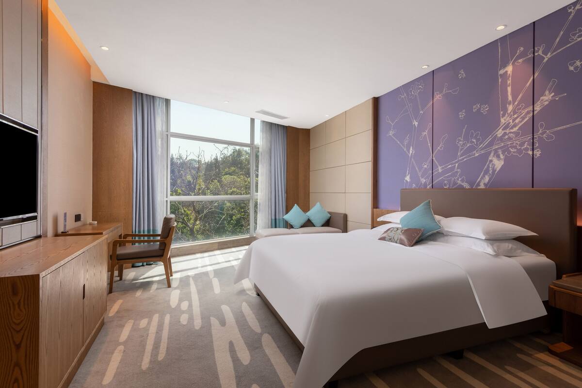 Una habitación de hotel moderna con una cama grande, un escritorio y un televisor.